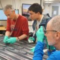 Three researchers analysing different sized rocks 